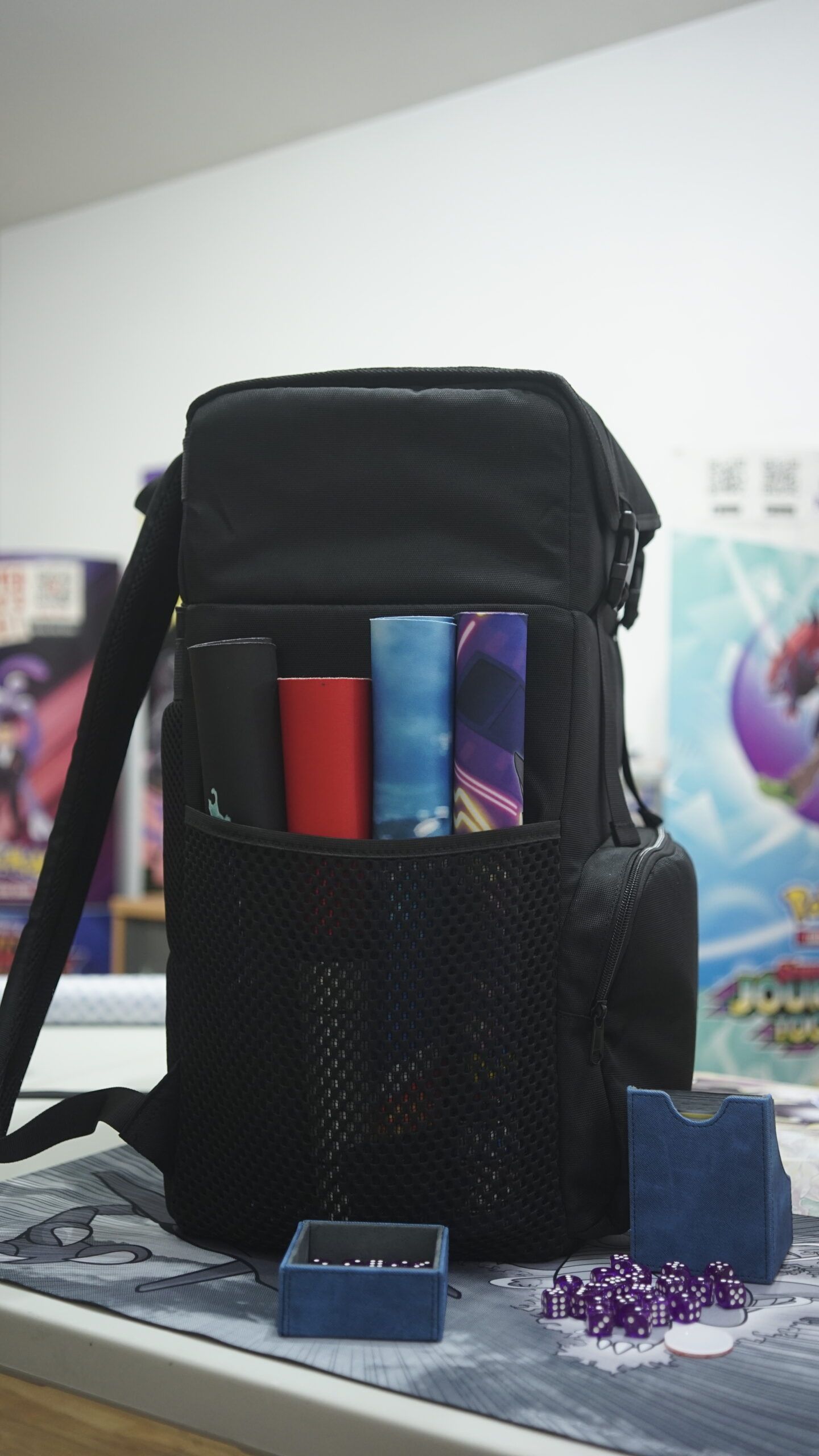 QUAD TCG backpack on a gaming table at a TCG league night shown containing four playmats